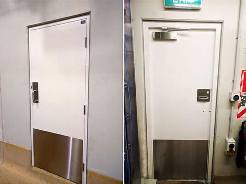 White industrial fire doors with stainless steel kick plates and door closers.